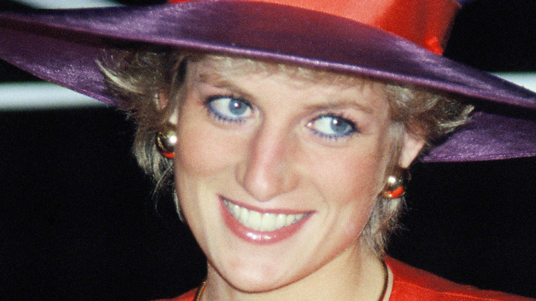 Princess Diana smiling and wearing purple hat