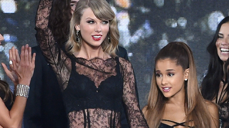 Taylor Swift and Ariana Grande smile onstage of the 2014 Victoria's Secret fashion show