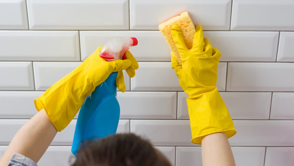 Woman cleaning a tiled wall