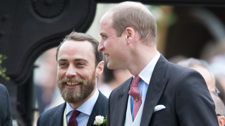 James Middleton smiling and walking with Prince William