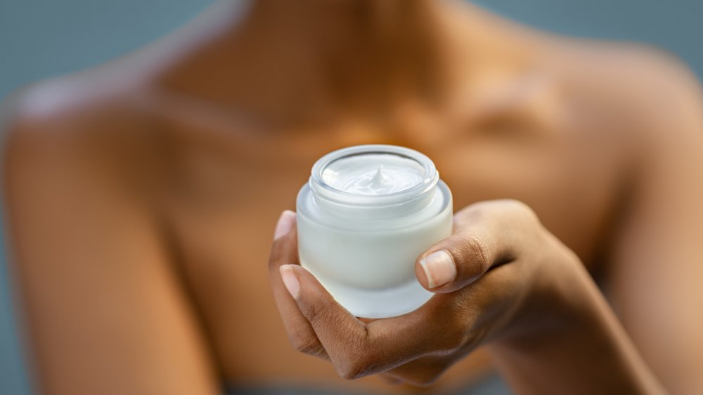 A woman holding a jar of cream