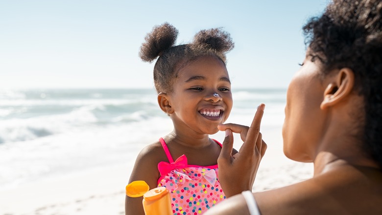 Woman applying sunscreen to child's face