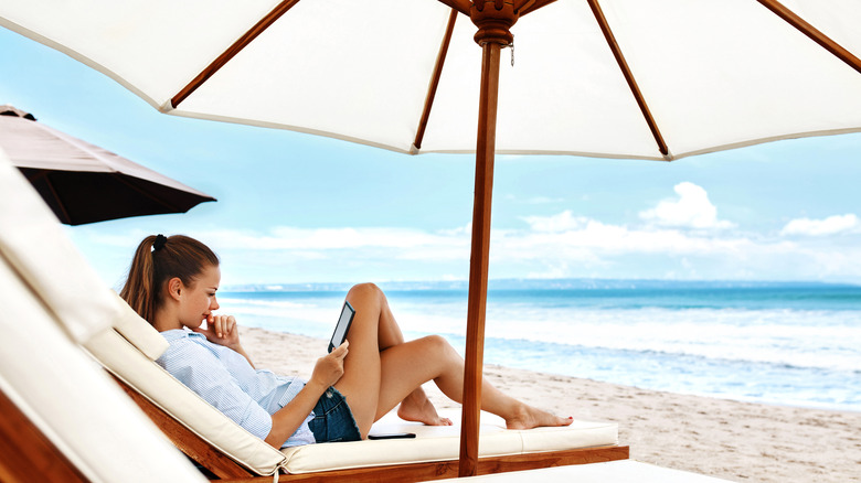 woman reading under umbrella at beach