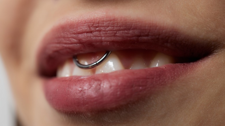 Woman showing teeth and smiley piercing 