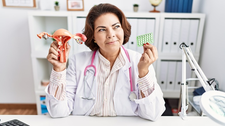 doctor holding anatomical model and birth control