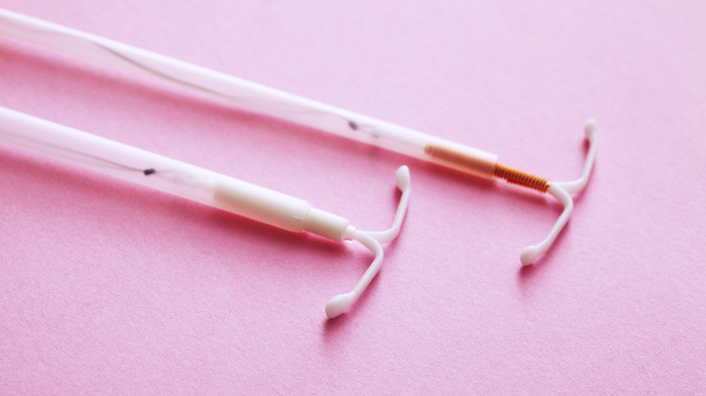 Two IUDs against pink background