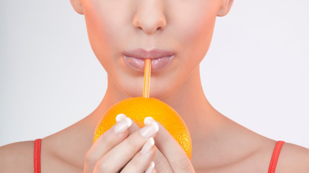 Woman drinking vitamin C from an orange