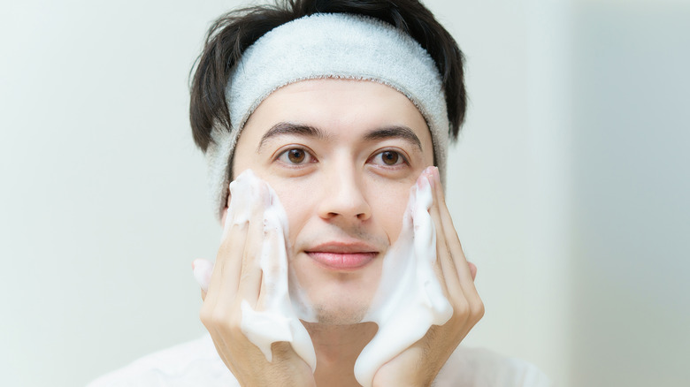 man washing face with foamy cleanser