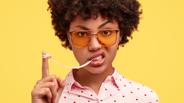 woman with strand of gum stretched out to finger