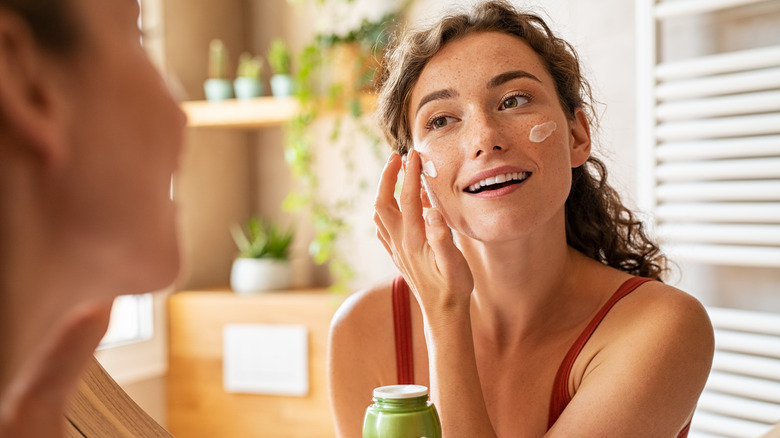 woman applying cream to face