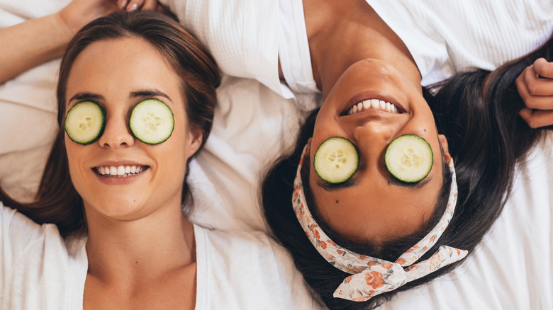 women smiling with cucumbers on eyes 