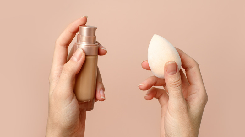 Person holding beauty blender and foundation 