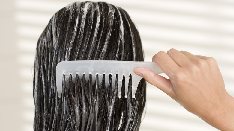 woman combing conditioner in hair