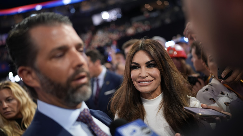 Kimberly Guilfoyle smiling at Donald Trump Jr. who's talking to reporters at convention