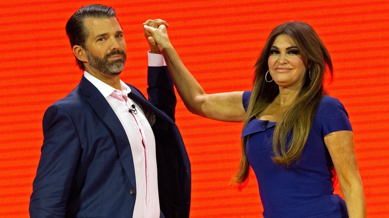 Donald Trump Jr. and Kimberly Guilfoyle holding hands on stage