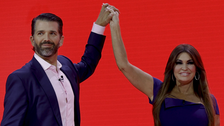 Donald Trump Jr. and Kimberly Guilfoyle holding raised hands