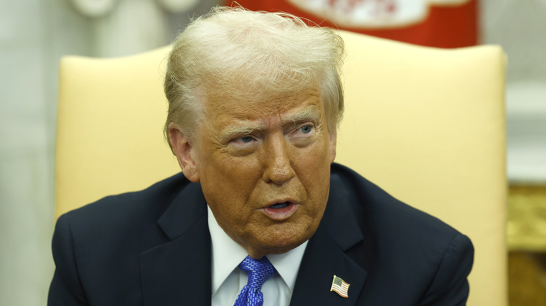 Donald Trump sits in a yellow chair in the Oval Office