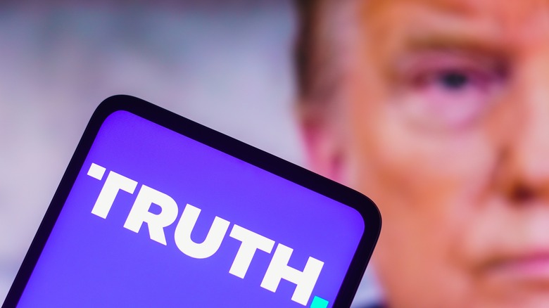 Donald Trump behind a phone with the Truth Social logo