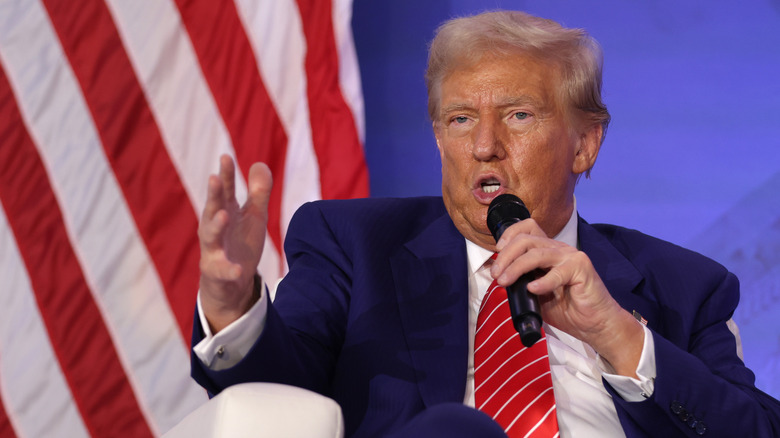 Donald Trump with microphone sitting and gesturing