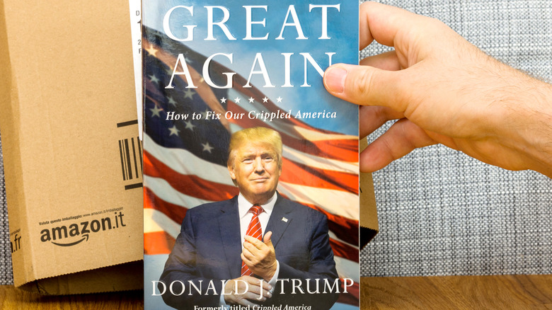 Hand holding book by Donald Trump