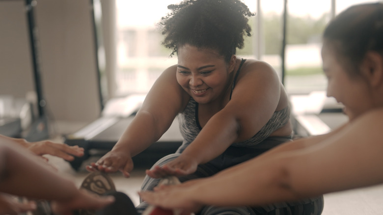 smiling women stretching at gym