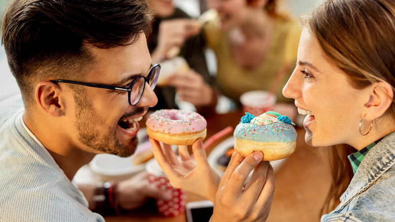 couple feeding each other doughnuts