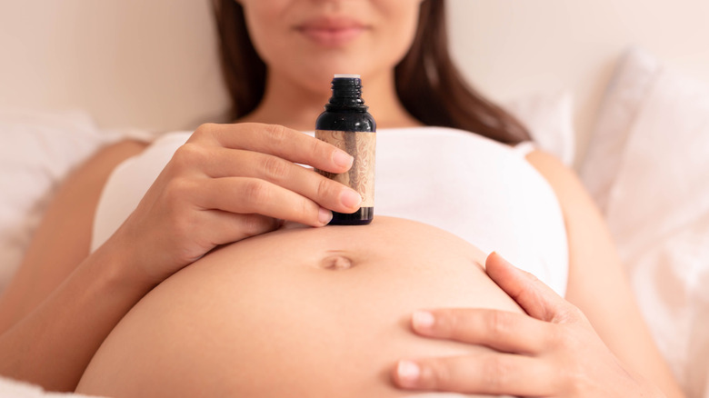 A pregnant woman holding a cosmetic bottle