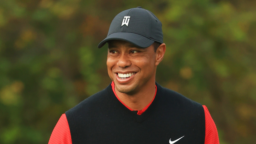 Tiger Woods smiling in baseball hat and black vest