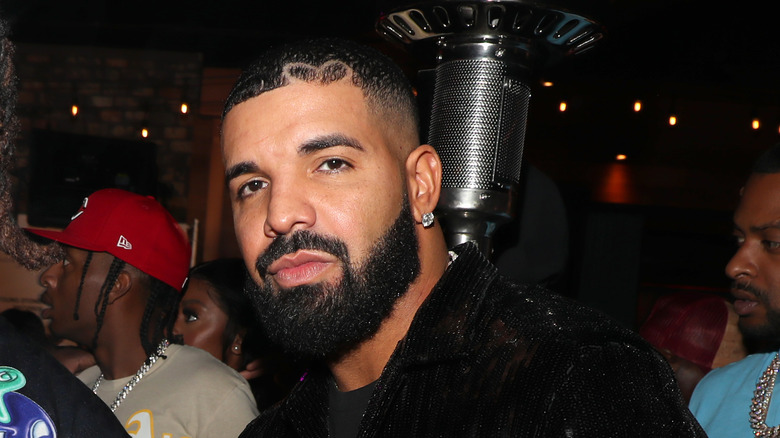 Drake standing in front of a microphone with a heart-shaped hairline