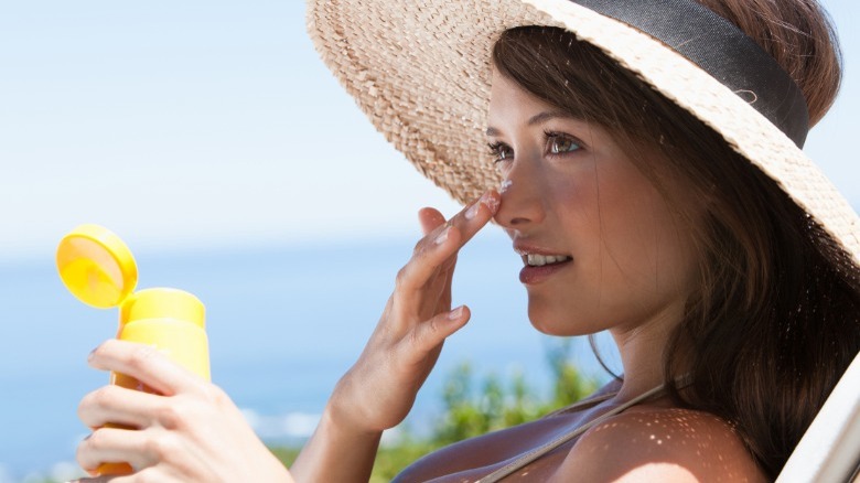 Woman applying sunscreen to nose