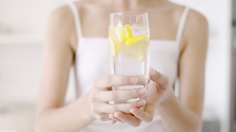 Woman holding glass of lemon water