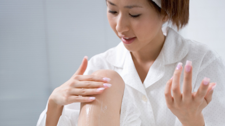 Woman rubbing lotion on leg 