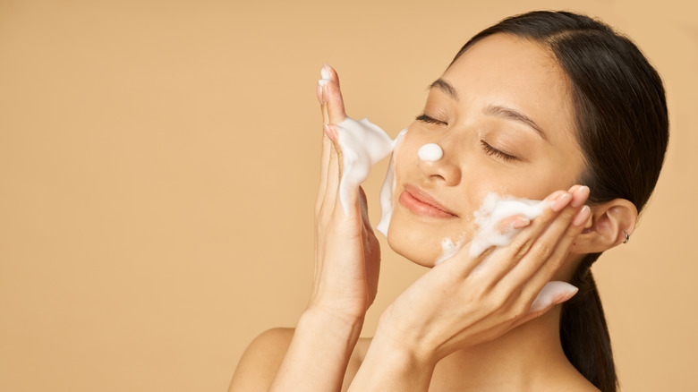 Woman with foaming cleanser on her face