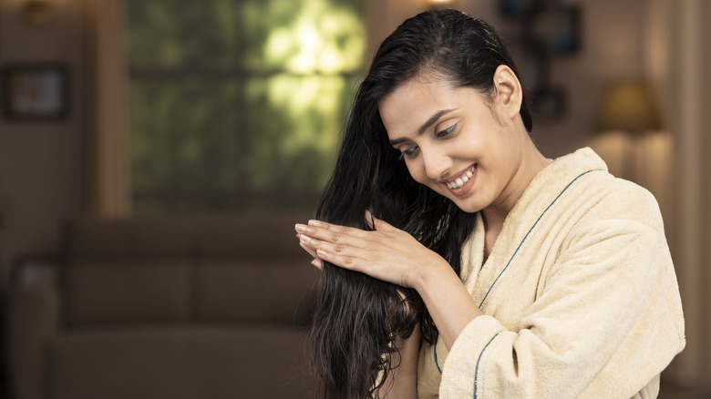 Woman adding oil to hair