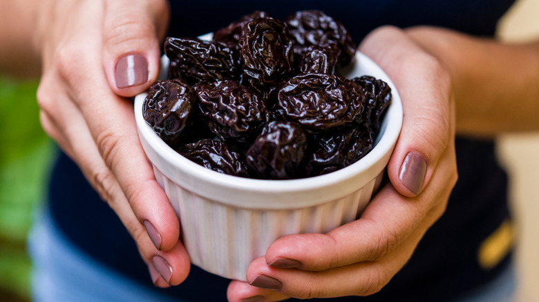 Woman holding a small bowl of prunes