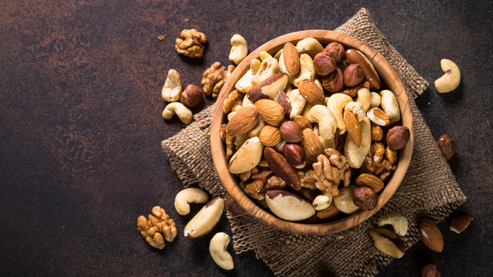 a wooden bowl filled with mixed nuts 