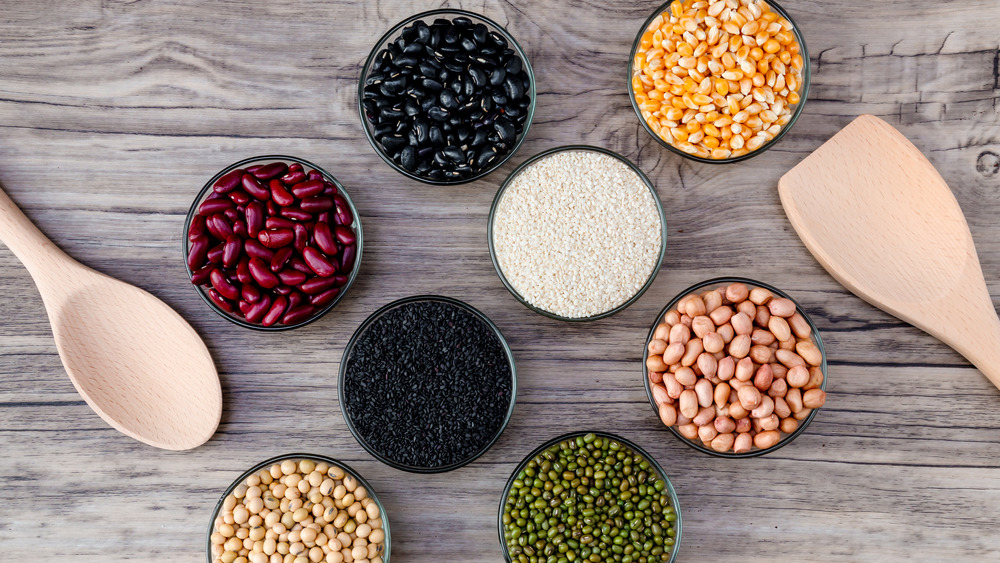 different types of beans and seeds separated in bowls