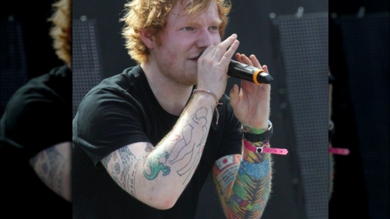 Ed Sheeran performing with both arm tattoo sleeves visible