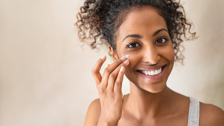 Woman applying cream to her face