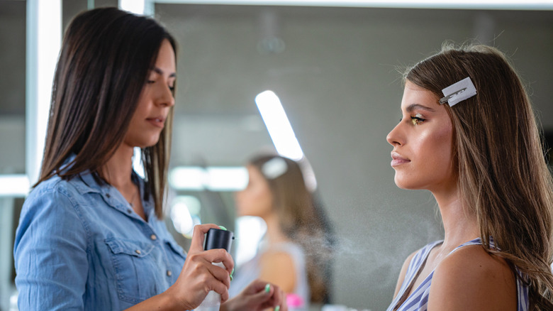 makeup artist applying setting spray to model