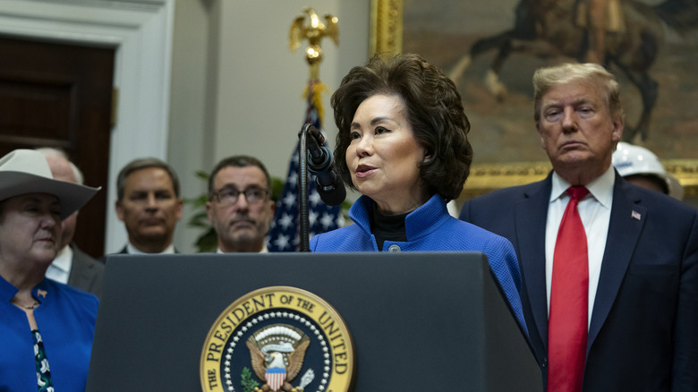 Donald Trump standing behind Elaine Chao