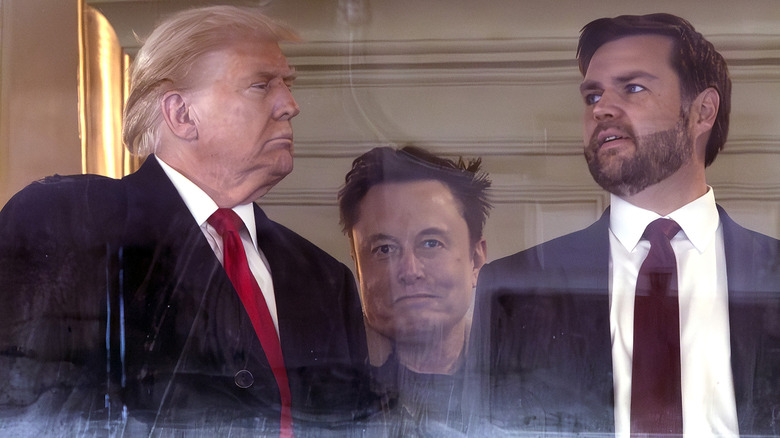 Donald Trump and JD Vance have a conversation and Elon Musk stands behind them