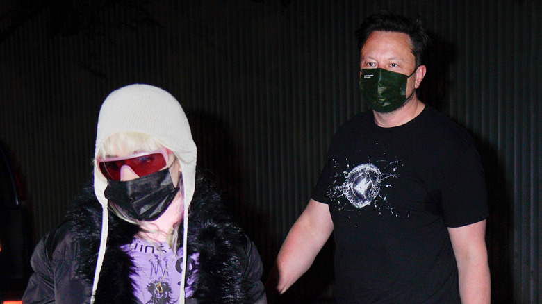 Grimes and Elon Musk wearing masks in a dark room