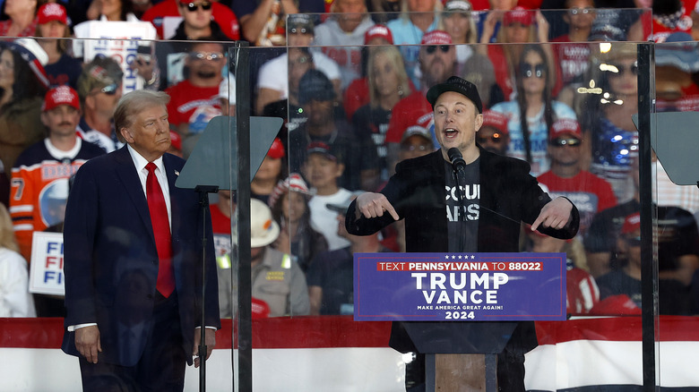 Donald Trump listens while Elon Musk makes a speech