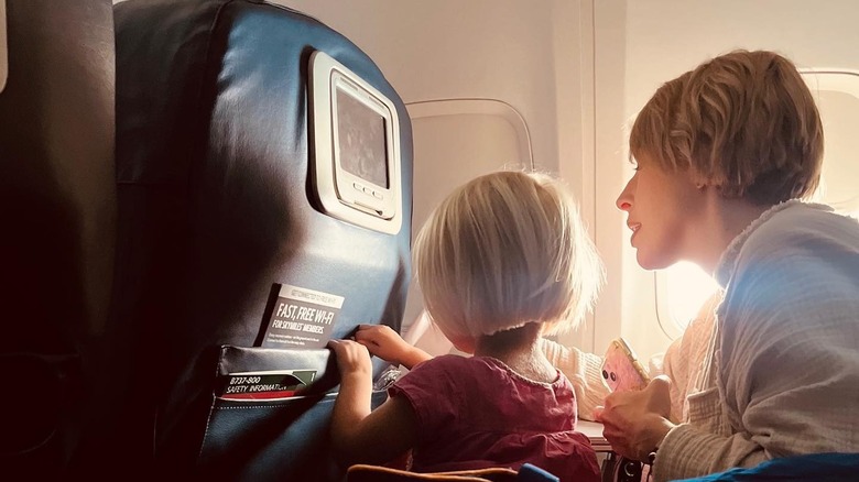 Erin sits with one of her children on an airplane 