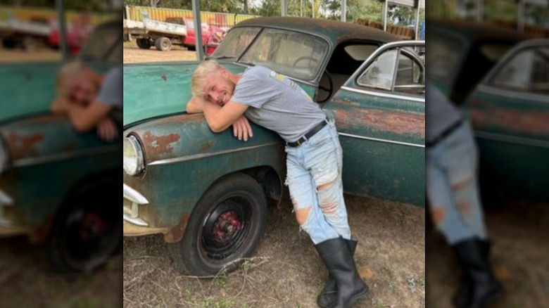 Ethan Plath posing with old car
