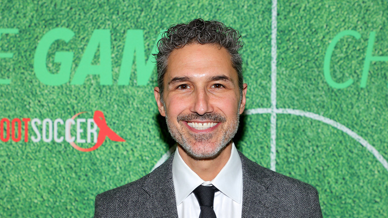 Ethan Zohn in suit in front of green background