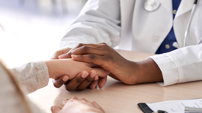 Doctor holding woman's hand