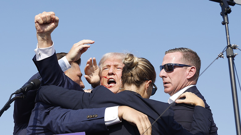 Donald Trump raising his fist surrounded by secret service after getting shot at