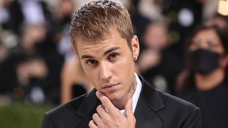 Justin Bieber in a suit touching his finger to his chin